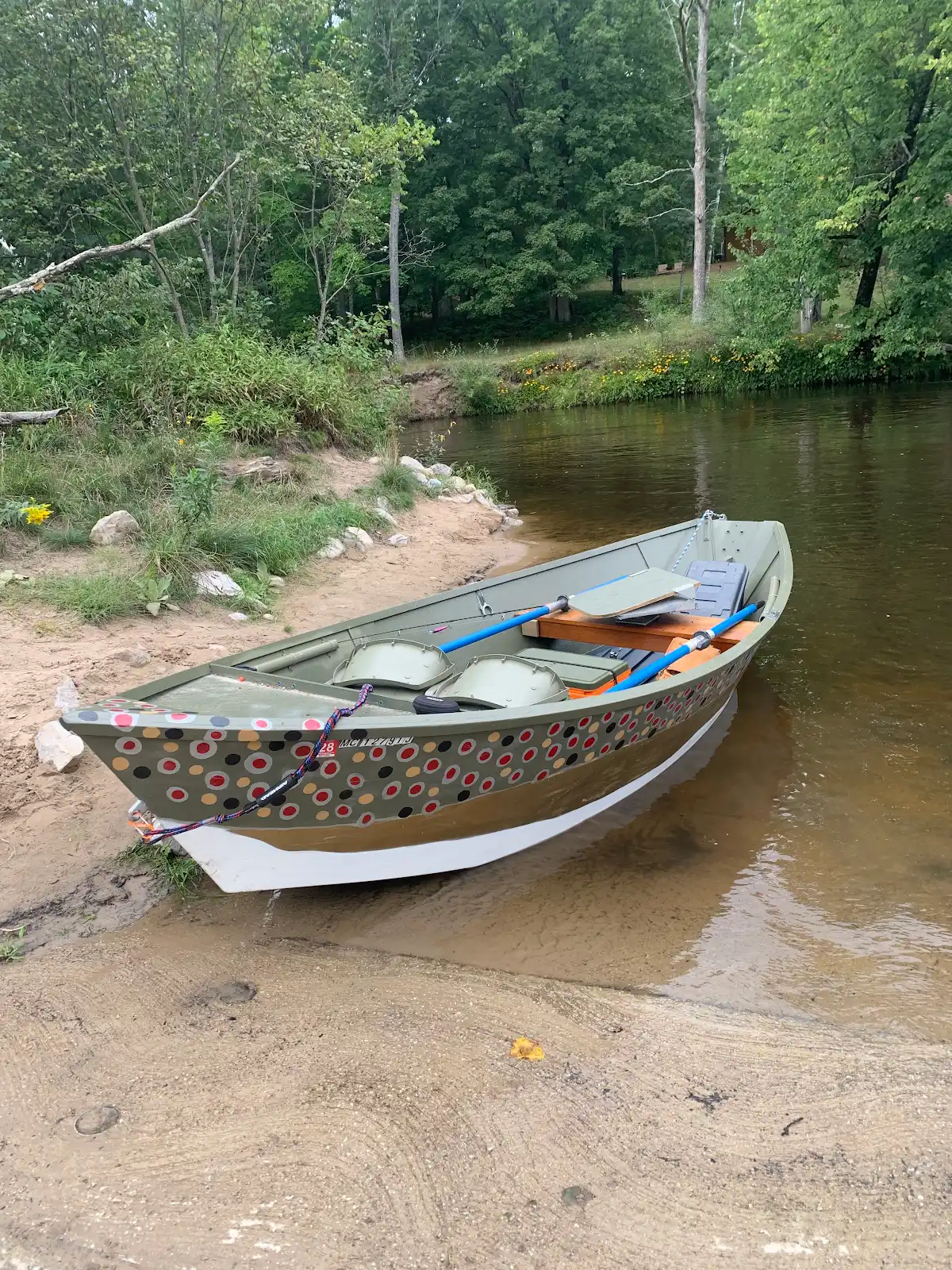 Painted drift boat resting at the boat ramp