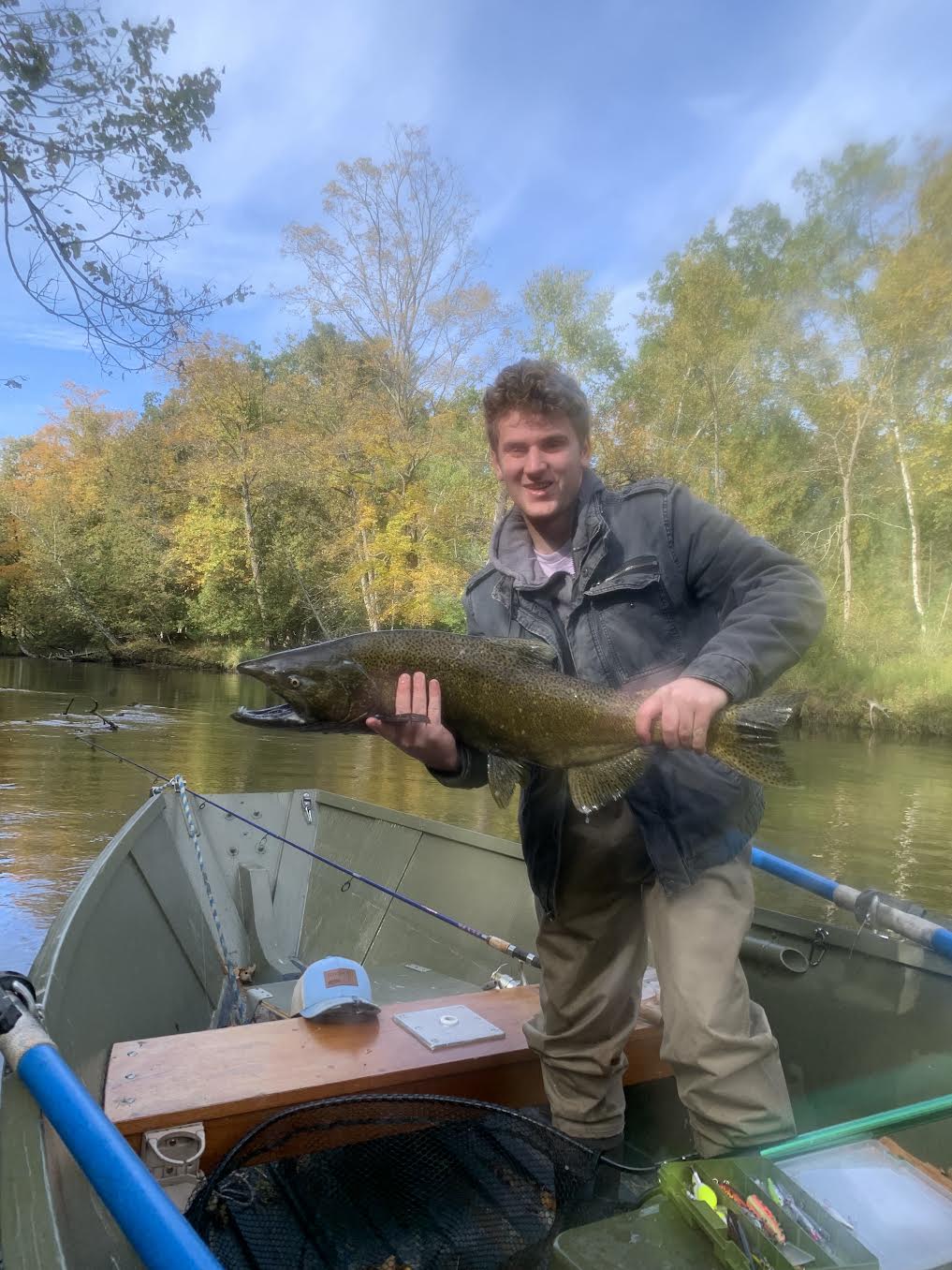 Young angler holding a huge Chinook salmon in the boat