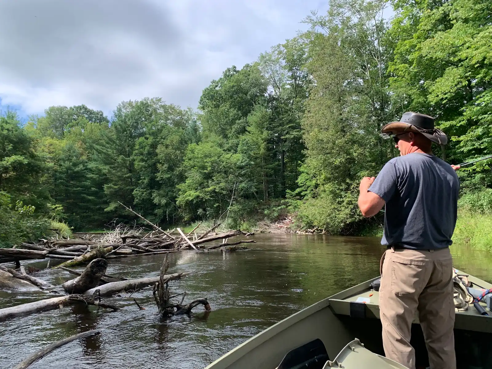 Angler casting near a log jam from the drift boat