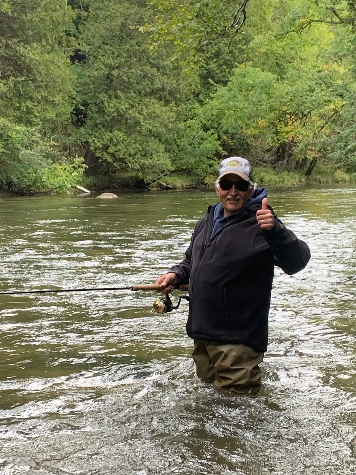 Smiling angler standing in the river with a spinning rod